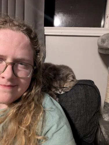 myself, long hair, blonde, next to dans cat maria, who is sleeping behind me on a couch
